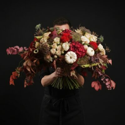 Le Signature : "Héritage & Passion" ​Finaliste Coupe de France 2019 ​L'Âme de la Création : Une Histoire de Concours ​Ce bouquet n'est pas une simple composition, c'est une pièce d'exception qui porte en elle l'émotion et l'exigence de la Coupe de France 2019. Réalisé pour l'épreuve du "Bouquet Signature", il incarne l'identité même de notre maison : une générosité sans limite et une opulence assumée. Chaque tige a été pensée pour représenter notre vision de l'art floral : un travail rigoureux sur les contrastes, les textures et le mouvement. ​Une Éthique d'Excellence : 100% France, 100% Saison ​Fidèles à nos valeurs et à notre terre, nous avons conçu ce bouquet comme un hommage au patrimoine horticole français : ​Origine Garantie : Un bouquet confectionné exclusivement à partir de fleurs 100% de saison et 100% Fleurs de France. ​La Noblesse du Rouge & Blanc : Un contraste saisissant entre la profondeur des hortensias rouge velours, la passion des roses rouges et la pureté lumineuse des roses branchues blanches. ​Architecture Végétale : Une structure complexe alliant la force des tiges de polygonum, la souplesse des feuilles de vigne et la douceur texturée du sedum. ​Nuances & Finitions : Des touches d'eucalyptus teintées pour une profondeur chromatique unique. ​Le Rythme de la Nature ​Parce qu'un bouquet signature vit au rythme des saisons, cette création évolue pour rester toujours exceptionnelle. Selon la période de l'année, nous y intégrons des éléments de décoration naturels qui renforcent son caractère authentique : ​En automne : Des coloquintes et petits cucurbitacées nichés au cœur des fleurs. ​Au fil des mois : Des fruits de saison et des trésors de la nature qui rendent chaque exemplaire strictement unique.