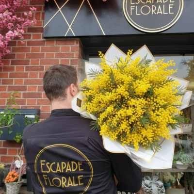 Le Bouquet "Nuage de Mimosa" ​Type de produit : Bouquet de prestige XXL Style : Volumineux, moderne et monochrome Disponibilité : Roncq & Wervicq-Sud ​Composition du bouquet ​Cette réalisation se distingue par sa structure imposante et son élégance minimaliste, mettant en avant la générosité d'une seule variété florale. ​Fleur principale : Mimosa  ​Habillage : ​Structure de papier kraft blanc et liseré doré : Un emballage rigide en corolle qui soutient le poids des fleurs tout en créant un contraste lumineux. ou Bleu ​Signature : Présenté avec le savoir-faire artisanal de l'équipe Escapade Florale. ​Conseils d'Expert pour la Durabilité ​Hydratation maximale : Le Mimosa  est très gourmand en eau. mais surtout pas d eau froide ​Préparation des tiges : Pour une meilleure absorption, recouper les tiges tous les 2 jours ​Eau fraîche : Changez l'eau du vase quotidiennement en veillant à ce qu'elle soit toujours propre et abondante. ​Points de vente ​Retrouvez cette création exclusive dans nos deux boutiques : ​Escapade Florale - Roncq : 10 rue Jules Cornard, 59223 Roncq. ​Escapade Florale by Sam - Wervicq-Sud : 51 rue Gabriel Péri, 59117 Wervicq-Sud.