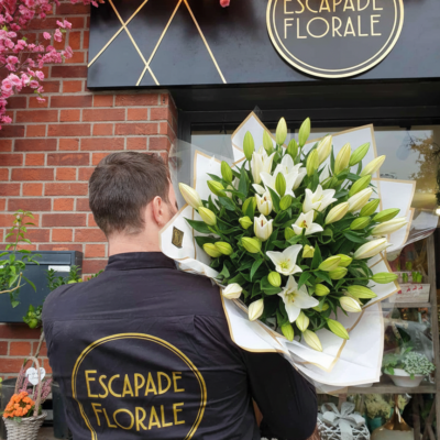 Le Bouquet "Nuage de Lys" ​Type de produit : Bouquet de prestige XXL Style : Volumineux, moderne et monochrome Disponibilité : Roncq & Wervicq-Sud ​Composition du bouquet ​Cette réalisation se distingue par sa structure imposante et son élégance minimaliste, mettant en avant la générosité d'une seule variété florale. ​Fleur principale : ​Lys Oriental Blanc ​Habillage : ​Structure de papier kraft blanc et liseré doré : Un emballage rigide en corolle qui soutient le poids des fleurs tout en créant un contraste lumineux. ou Bleu ​Signature : Présenté avec le savoir-faire artisanal de l'équipe Escapade Florale. ​Conseils d'Expert pour la Durabilité ​Hydratation maximale : Le Lys est très gourmand en eau.  ​Préparation des tiges : Pour une meilleure absorption, recouper les tiges tous les 2 jours ​Eau fraîche : Changez l'eau du vase quotidiennement en veillant à ce qu'elle soit toujours propre et abondante. ​Points de vente ​Retrouvez cette création exclusive dans nos deux boutiques : ​Escapade Florale - Roncq : 10 rue Jules Cornard, 59223 Roncq. ​Escapade Florale by Sam - Wervicq-Sud : 51 rue Gabriel Péri, 59117 Wervicq-Sud.