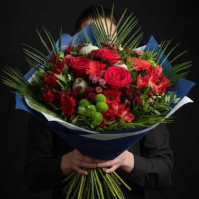 Bouquet "Rouge Passion" ​L'Esprit de la Création ​Une composition intense et vibrante qui célèbre la force des sentiments. Ce bouquet généreux joue sur un camaïeu de rouges profonds, dynamisé par des touches de vert acidulé pour un rendu moderne et plein de vie. C’est le choix idéal pour exprimer une passion, un amour sincère ou pour apporter une chaleur immédiate à un intérieur. ​Détails de la Composition ​Chaque bouquet est une pièce unique, assemblée avec passion par nos artisans fleuristes : ​Fleurs Majeures : De magnifiques roses rouges aux pétales veloutés, symboles absolus de l'élégance. ​Cœur de Bouquet : Un mélange harmonieux d'alstroemerias rouges et de germinis rouges pour une densité florale généreuse. ​Contrastes & Textures : Des Santinis verts pompon qui apportent du relief et de la fraîcheur, accompagnés de délicates fleurettes rouges pour la finesse. ​Écrin Végétal : Un travail sur le feuillage graphique (palmier) qui donne au bouquet une envergure spectaculaire et une tenue parfaite. ​Le Conseil de l'Artisan ​"Le rouge est une couleur qui capte la lumière. Pour préserver l'éclat de vos roses et des alstroemerias, nous vous conseillons de recouper les tiges en biseau et de changer l'eau tous les deux jours. Maintenez le bouquet loin des sources de chaleur pour prolonger sa tenue exceptionnelle." ​Service & Livraison ​Retrouvez cette création dans nos deux points de vente : ​Escapade Florale - Roncq : 10 rue Jules Cornard, 59223 Roncq. ​Escapade Florale by Sam - Wervicq-Sud : 51 rue Gabriel Péri, 59117 Wervicq-Sud. ​Livraison : Nous assurons la livraison sur les secteurs de Roncq, Wervicq-Sud et les environs.
