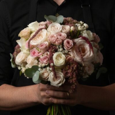 Bouquet de Mariée "Éclat Romantique" ​L'Esprit de la Création ​Une composition nuptiale généreuse et raffinée, conçue pour sublimer votre grand jour avec une élégance intemporelle. Ce bouquet se distingue par son travail de textures remarquable, où la noblesse de la rose rencontre le charme champêtre de l'amarante et du sedum. Ses nuances de blanc pur et de rose poudré créent une harmonie douce et lumineuse, parfaite pour un mariage romantique et sophistiqué. ​Détails de la Composition ​Chaque bouquet de mariée est une pièce d'orfèvrerie végétale, réalisée sur mesure avec les plus belles variétés : ​Les Roses : Un mélange somptueux de roses blanches et de roses roses, travaillées en gros boutons pour la majesté et en petits boutons pour la délicatesse. ​Le Surfaçage : Des retombées d'amarante qui apportent une touche sculpturale et un mouvement gracieux à l'ensemble. ​Textures & Relief : L'utilisation du sedum et du gypsophile crée un aspect vaporeux et moderne, offrant un contraste subtil avec le velouté des roses. ​Écrin Végétal : Quelques feuilles d'eucalyptus aux reflets argentés viennent parfaire le bouquet, apportant une note de fraîcheur et un parfum délicat. ​Le Conseil de l'Artisan ​"Le bouquet de mariée est l'accessoire central de votre tenue. Pour que vos roses restent éclatantes jusqu'au bout de la nuit, nous vous conseillons de le conserver dans un endroit frais jusqu'au moment de la cérémonie. Sa structure généreuse est idéale pour les robes de mariée de style princesse ou bohème chic." ​Service & Personnalisation ​Nous vous accompagnons dans la création de votre mariage depuis nos deux boutiques : ​Escapade Florale - Roncq : 10 rue Jules Cornard, 59223 Roncq. ​Escapade Florale by Sam - Wervicq-Sud : 51 rue Gabriel Péri, 59117 Wervicq-Sud. ​[ Prendre rendez-vous pour un devis mariage ]
