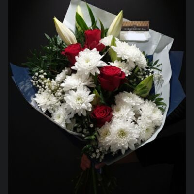 Bouquet "Éclat de Passion" ​Nom du produit : Composition Éclat de Passion Style : Élégant, contrasté et intemporel Disponibilité : Escapade Florale (Roncq & Wervicq-Sud) ​Description du produit ​Ce bouquet de prestige joue sur un contraste saisissant entre la pureté et la passion. Il réunit la noblesse de la rose rouge et la majesté du lys blanc, sublimées par la légèreté des chrysanthèmes et du gypsophile. Un habillage en corolle bleu nuit vient structurer l'ensemble pour une présentation moderne et haut de gamme. ​Composition florale ​Roses Rouges : Pour l'élégance et la profondeur. ​Lys Blancs : Pour la hauteur et le parfum délicat. ​Chrysanthèmes Blancs : Pour le volume et la texture. ​Gypsophile : Pour une touche vaporeuse. ​Feuillage Local : Issu de nos cultures pour une fraîcheur garantie. ​Conseils d'entretien ​Hydratation : Retaillez les tiges en biseau tous les deux jours. ​Emplacement : Maintenez le bouquet à l'écart des sources de chaleur et du soleil direct pour prolonger la tenue des lys. ​Eau : Changez l'eau du vase régulièrement (eau propre et fraîche). ​Points de vente ​Retrouvez cette création dans nos deux boutiques : ​Escapade Florale - Roncq : 10 rue Jules Cornard. ​Escapade Florale by Sam - Wervicq-Sud : 51 rue Gabriel Péri.